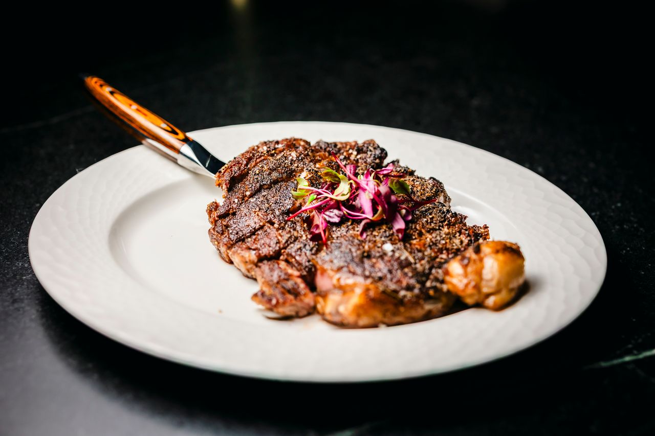 Peppercorn-crusted ribeye with micro herbs at The Boardroom Lafayette