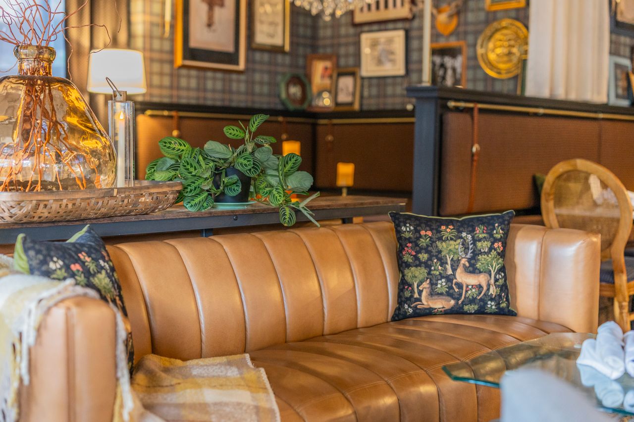 Channel-tufted leather sofa beneath framed gallery wall at The Boardroom