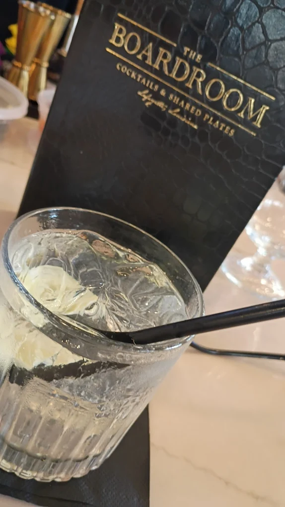 Handcrafted cocktail beside The Boardroom menu in Lafayette